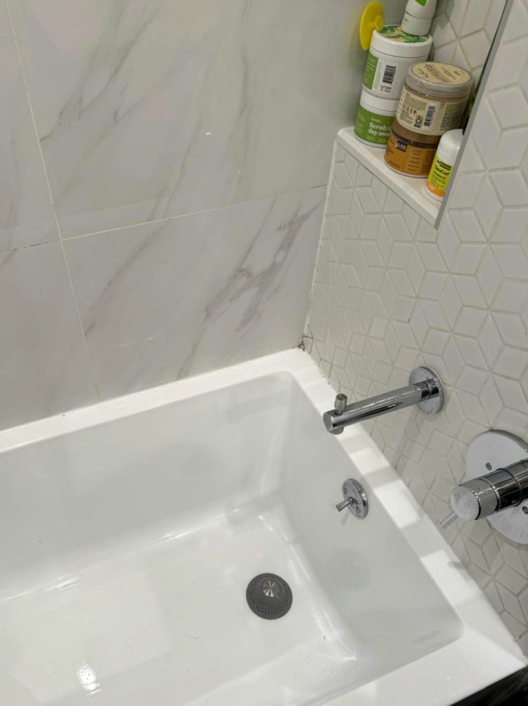 Cleaned and sanitized white bathroom tile and tub after Handedly deep clean